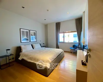Spacious modern bedroom with large window and stylish decor in luxury apartment.