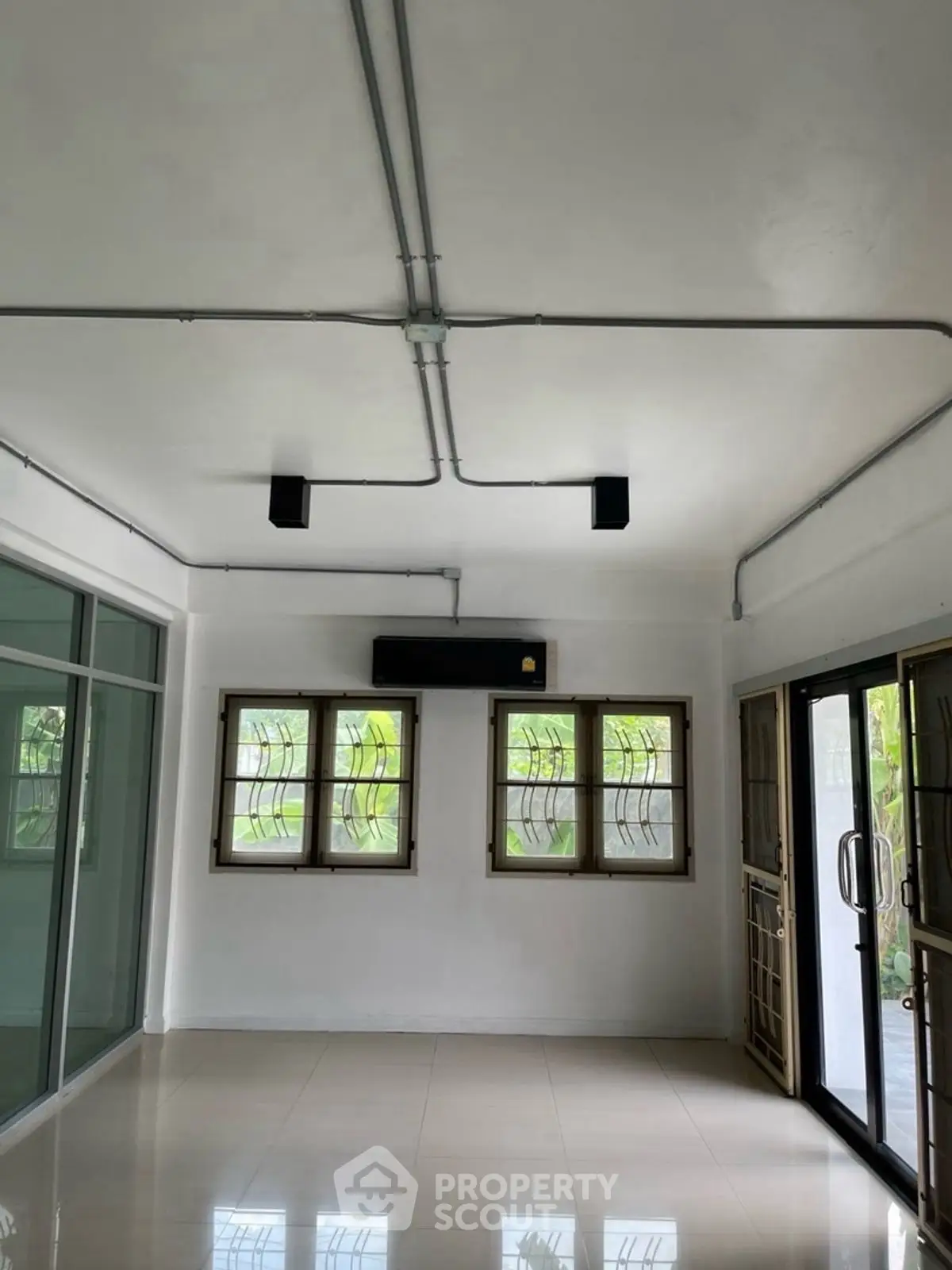 Spacious room with large windows and modern lighting, ideal for versatile living space.