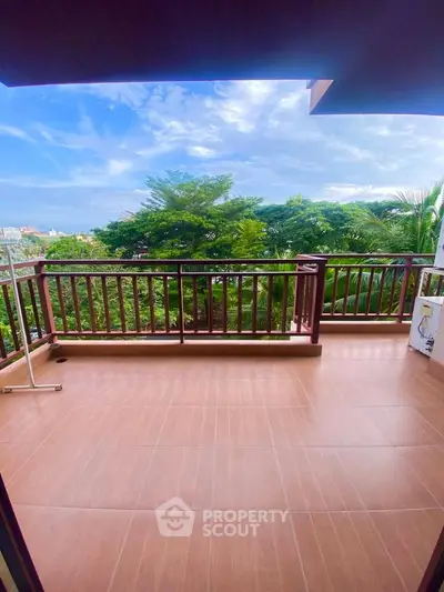 Spacious balcony with scenic green view and wooden railing, perfect for relaxation.