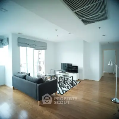 Spacious modern living room with hardwood floors and large windows offering natural light.