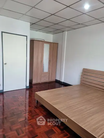 Spacious bedroom with wooden flooring and modern furniture in a minimalist design.