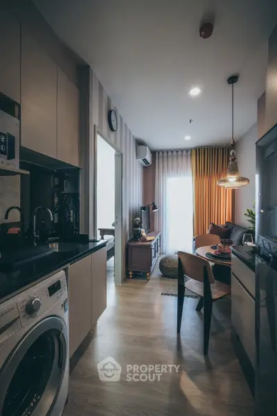 Modern apartment interior with kitchen and living area, featuring stylish decor and natural lighting.
