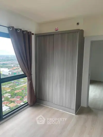 Modern bedroom with large window and built-in wardrobe offering stunning city views.