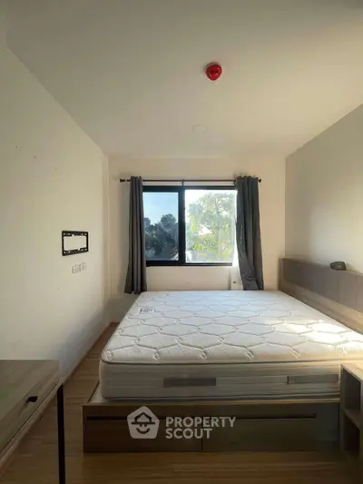 Bright bedroom with large window and modern furniture, showcasing a spacious and inviting atmosphere.