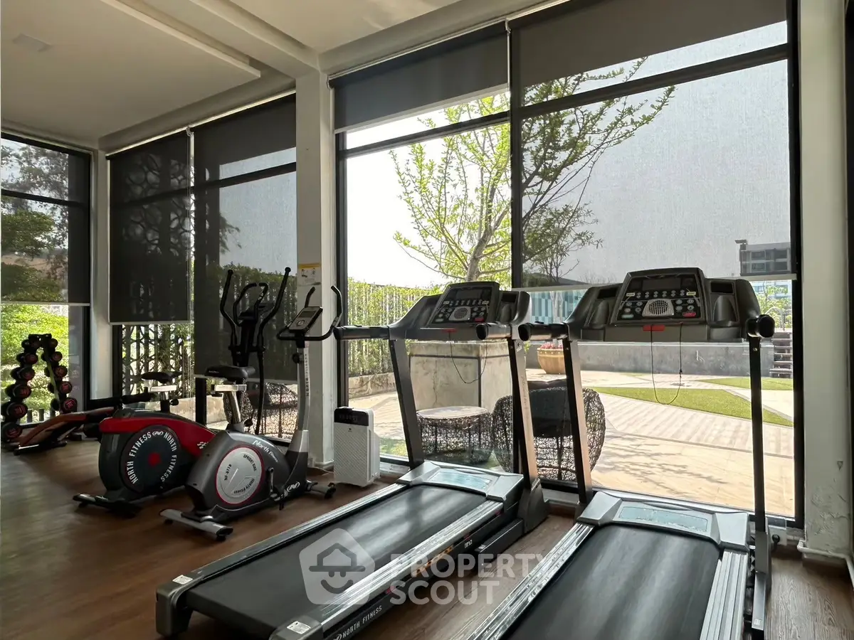 Modern gym with treadmills and outdoor view in luxury real estate property