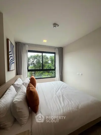 Cozy bedroom with large window offering lush green views, modern decor, and comfortable bedding.
