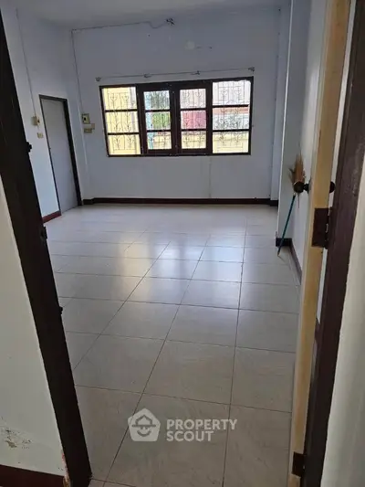 Spacious empty room with large windows and tiled flooring, perfect for customization.