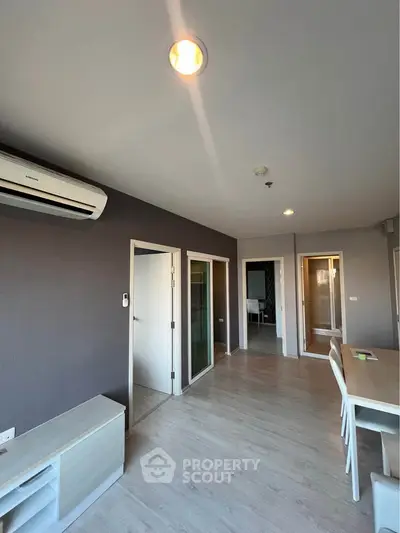Modern living room with sleek design and air conditioning, featuring wooden flooring and contemporary furniture.