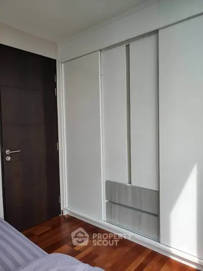 Modern bedroom with sleek built-in wardrobe and wooden flooring