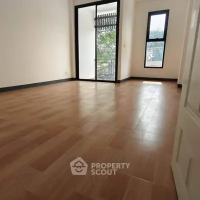 Spacious empty room with large windows and wooden flooring, ideal for customization.
