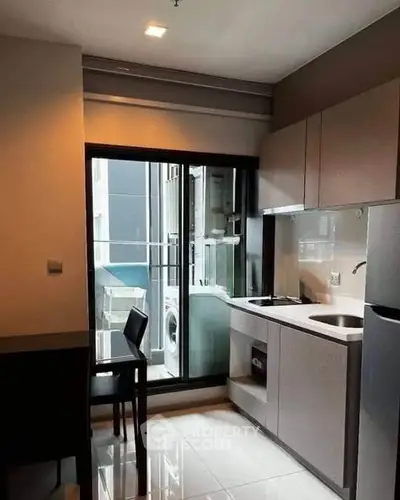 Modern kitchen with sleek cabinetry and balcony access in urban apartment