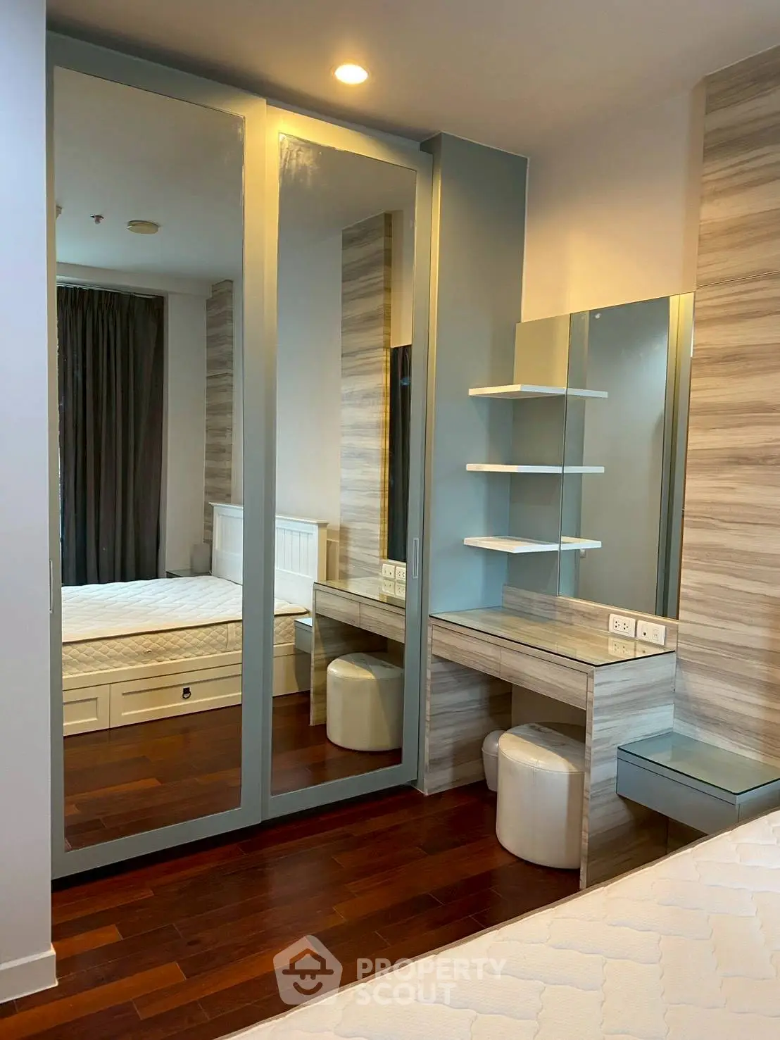 Modern bedroom with mirrored wardrobe and stylish vanity in a cozy apartment.