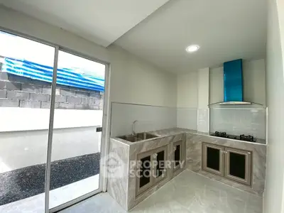 Modern kitchen with sleek design and gas stove, featuring ample natural light and stylish finishes.