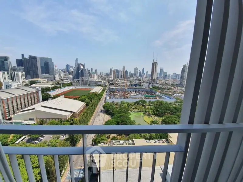 Stunning cityscape view from a high-rise balcony overlooking urban skyline and lush greenery.
