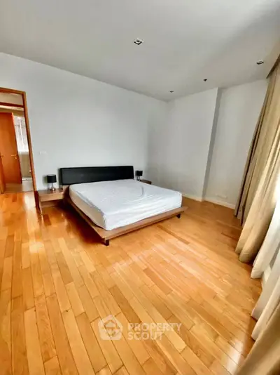 Spacious bedroom with wooden flooring and modern minimalist design