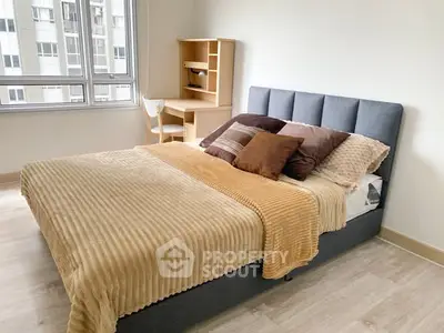 Modern bedroom with cozy bed and study desk, bright natural light from large window.