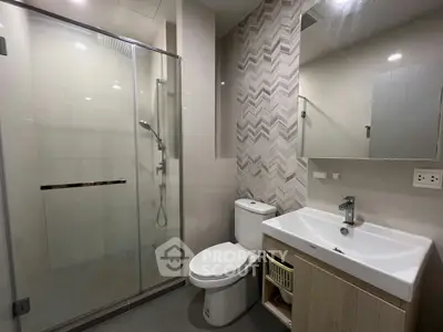 Modern bathroom with glass shower and sleek fixtures in contemporary apartment.