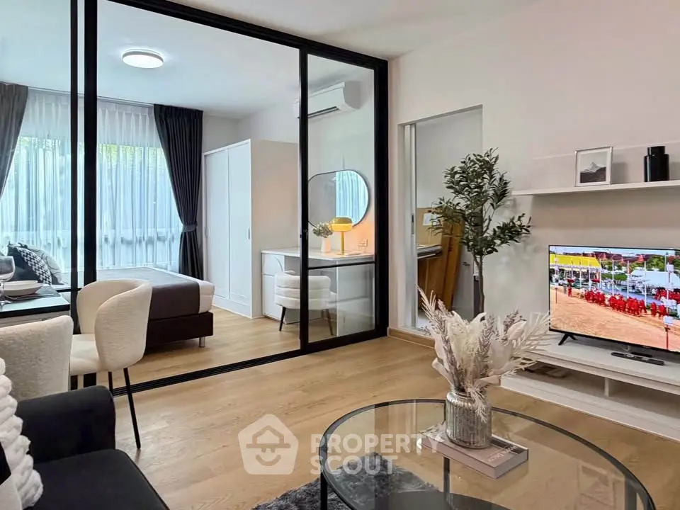 Modern living room with glass partition, stylish decor, and natural light in a contemporary apartment.