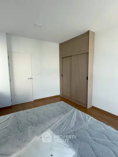 Spacious bedroom with wooden flooring and built-in wardrobe, perfect for modern living.