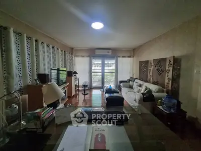 Spacious living room with modern decor and large windows offering natural light and garden view.