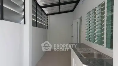 Modern kitchen with sleek design and ample natural light, featuring a stainless steel sink and minimalist decor.