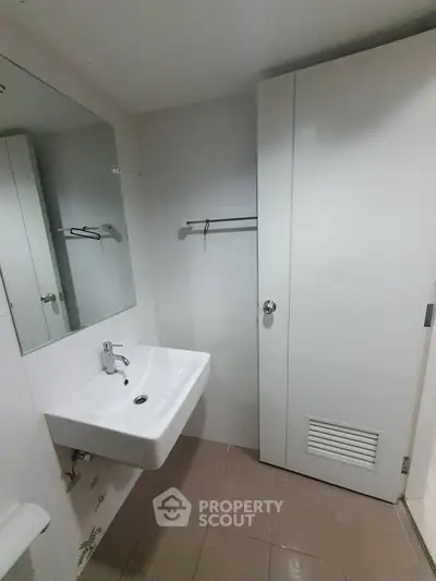 Modern bathroom with sleek white sink and large mirror in minimalist design.