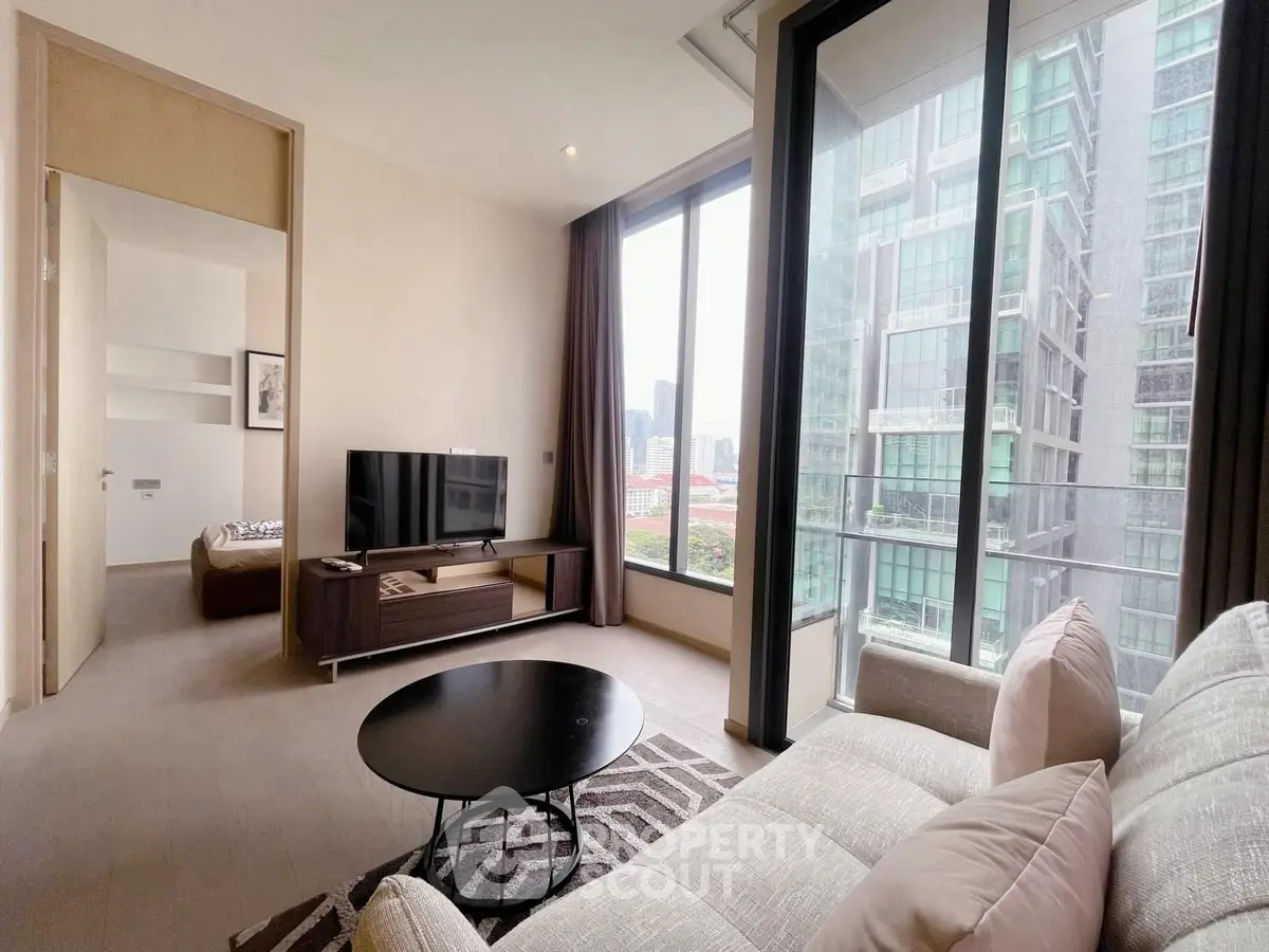 Modern living room with large windows and city view, featuring stylish furniture and natural light.