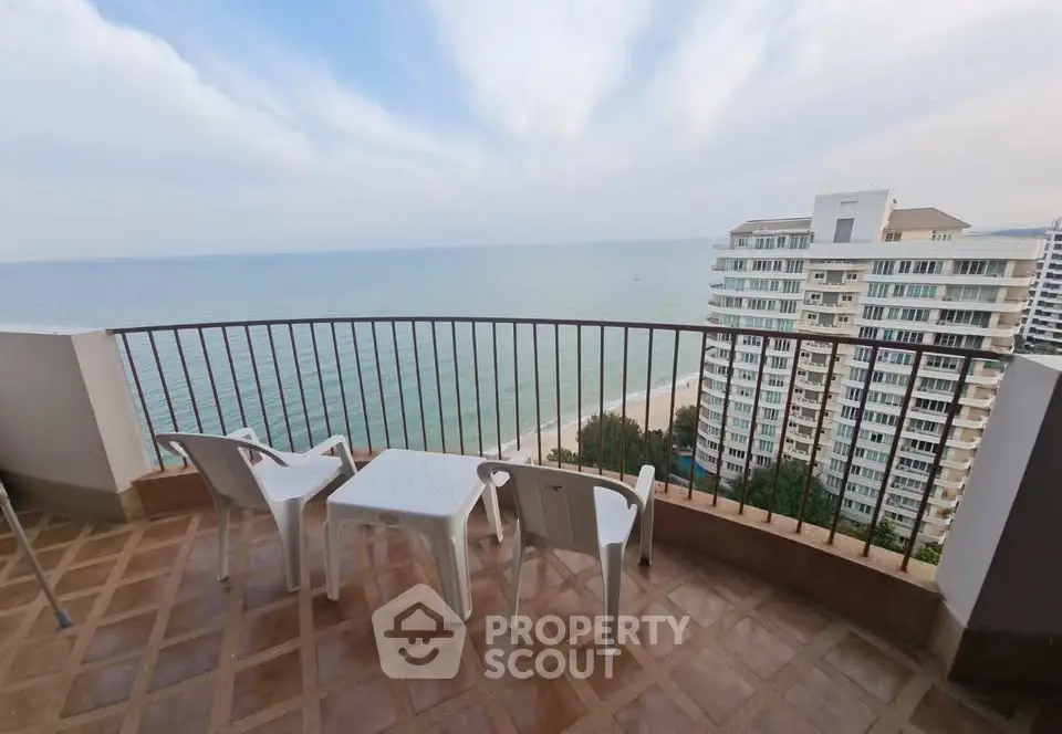 Stunning ocean view from spacious balcony with seating area in high-rise apartment.