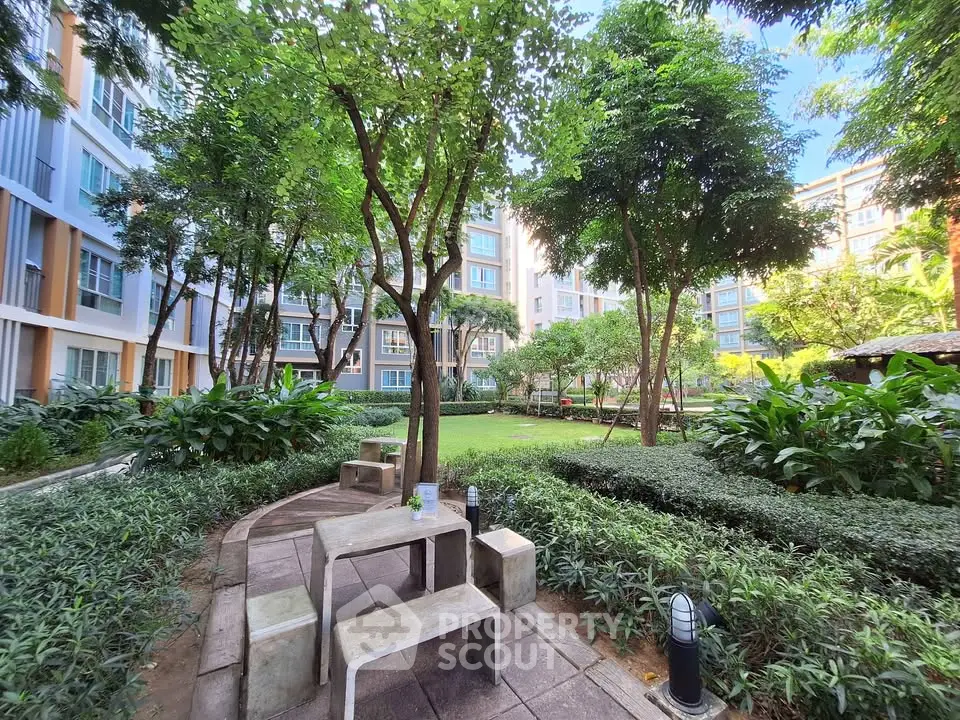 Lush garden view in modern apartment complex with seating area and vibrant greenery.