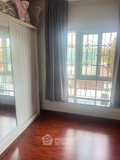 Bright bedroom with large window and wooden flooring