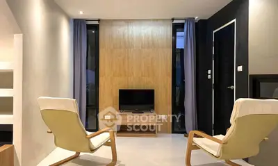 Modern living room with stylish chairs and a sleek TV setup, perfect for relaxation and entertainment.