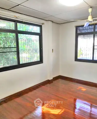Bright room with polished wooden floors and large windows, ideal for a cozy living space.