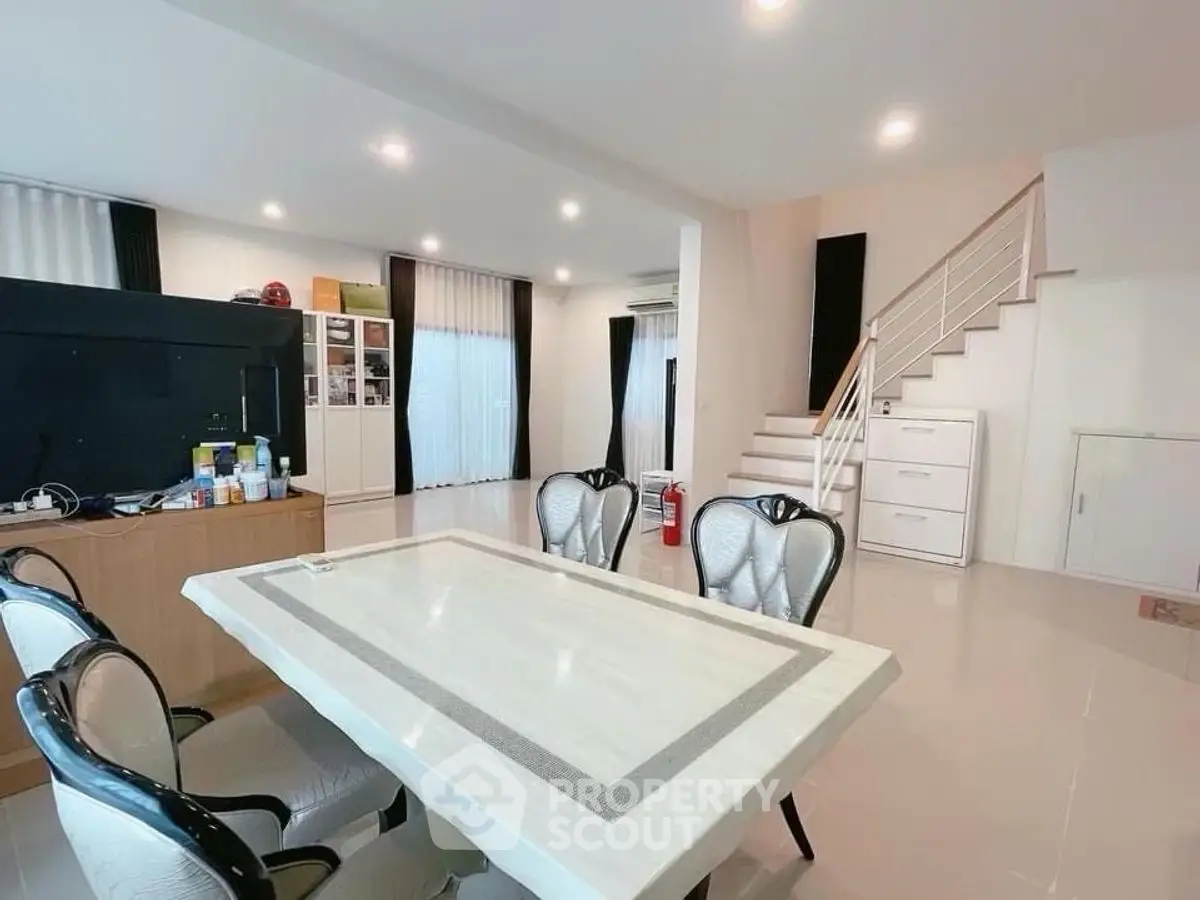 Spacious open-plan living and dining area with modern decor and staircase.