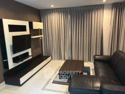 Modern living room with sleek black leather sofa and stylish entertainment unit
