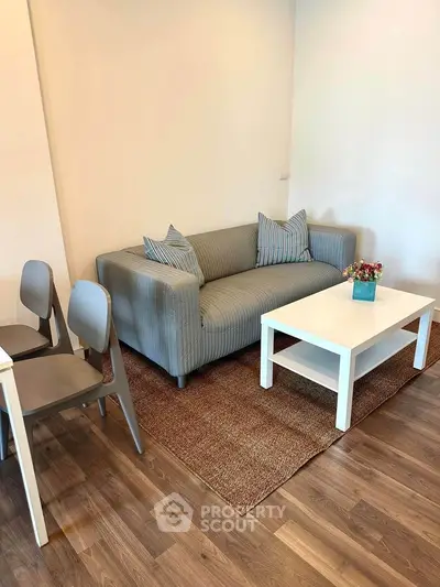 Cozy living room with modern gray sofa and white coffee table on wooden floor.