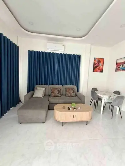 Modern living room with stylish sofa and dining area, featuring elegant decor and natural light.