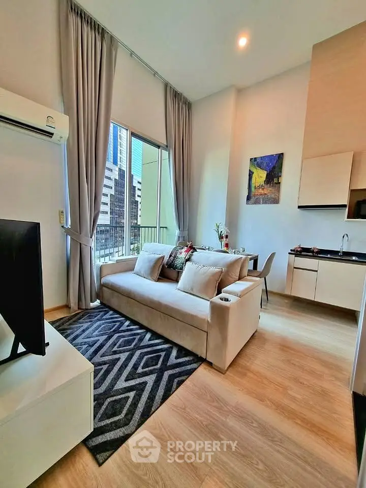Modern living room with high ceilings, large windows, and compact kitchen in a stylish apartment.