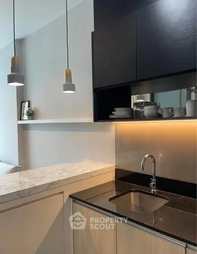 Modern kitchen with sleek design, featuring marble countertop and stylish pendant lighting.