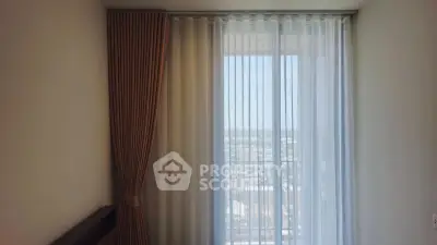 Elegant room with floor-to-ceiling window and sheer curtains offering a stunning city view.