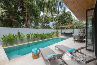 Luxurious tropical poolside oasis with lush greenery and modern outdoor seating area.