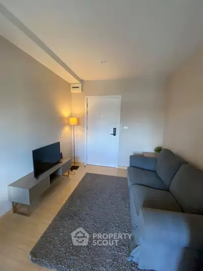 Cozy living room with modern sofa, TV, and warm lighting in a stylish apartment.