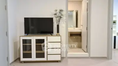 Modern living room with TV stand and view into a sleek bathroom
