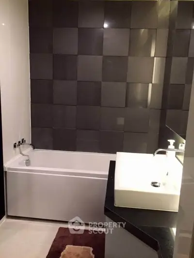Modern bathroom with sleek black tiles and a stylish bathtub.