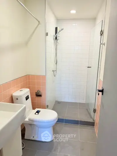 Modern bathroom with shower and pink tile accents in contemporary home.