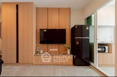 Modern living room with sleek TV setup and stylish black fridge