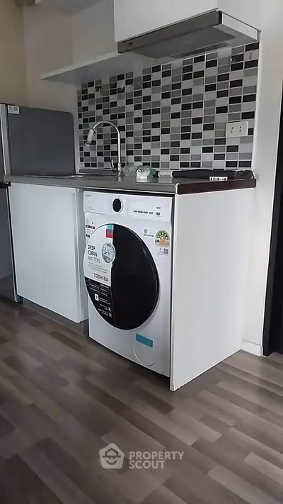 Modern kitchen with sleek appliances and stylish backsplash in a compact layout.