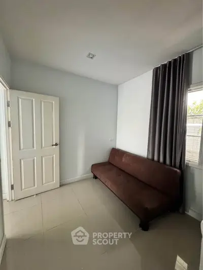 Cozy minimalist room with sleek brown sofa and natural light from window, perfect for relaxation.