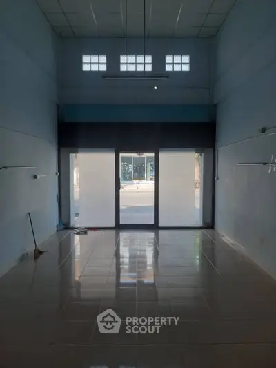 Spacious empty commercial space with large front windows and tiled flooring, ideal for retail or office setup.