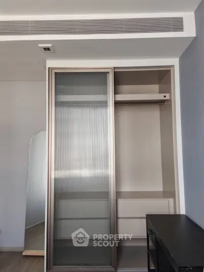 Modern closet with sliding door and built-in drawers in stylish apartment