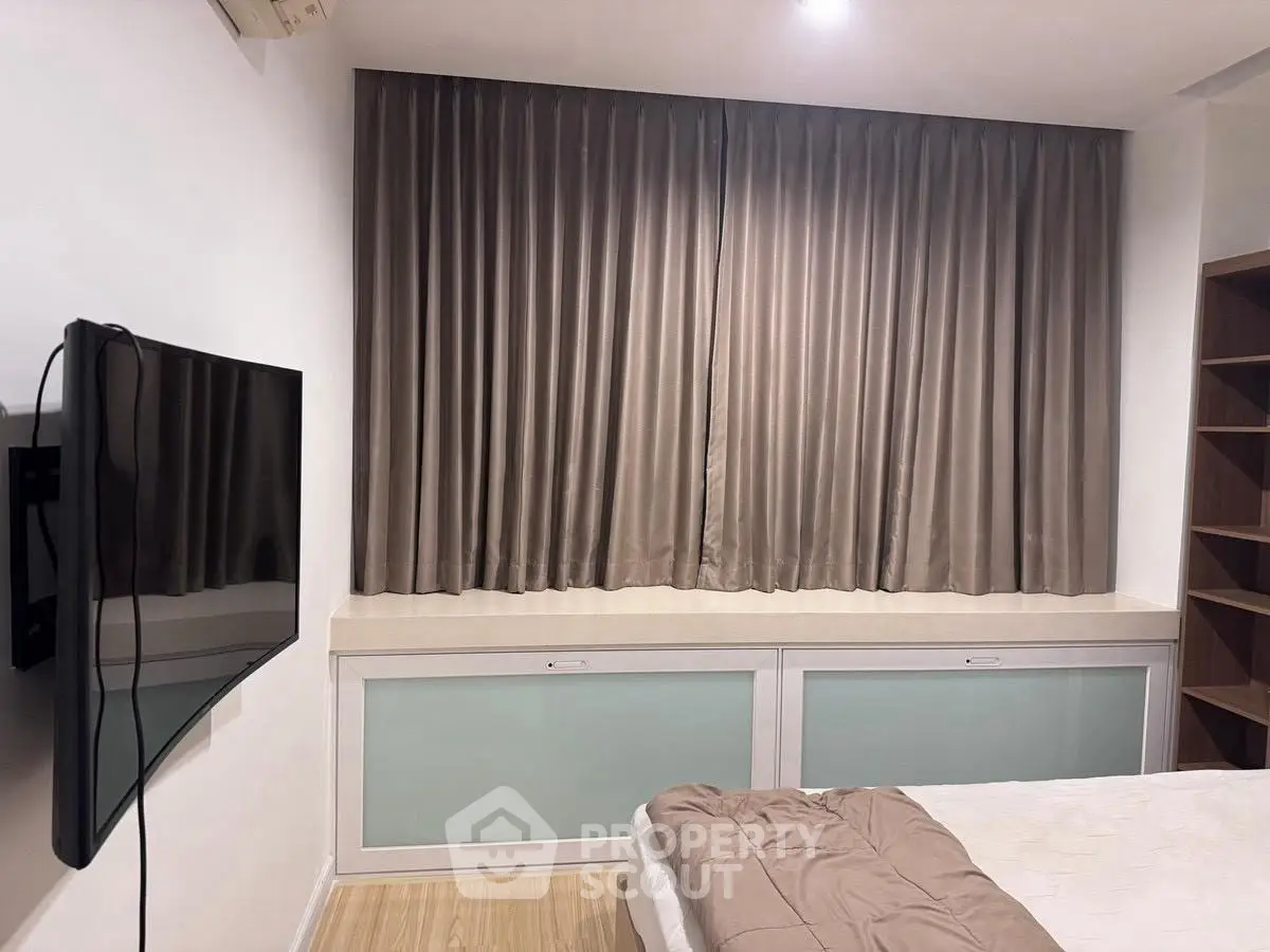 Cozy bedroom with wall-mounted TV and elegant curtains